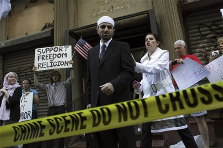 Imam Abdallah Adhani, center, leaves a proposed site for an Islamic cultural center to speak to reporters after a Aug. 27 prayer service followed by his media adviser Tara Bohen, right in New York. The NYPD set up barrier tape in front of the building to contain members of the media.